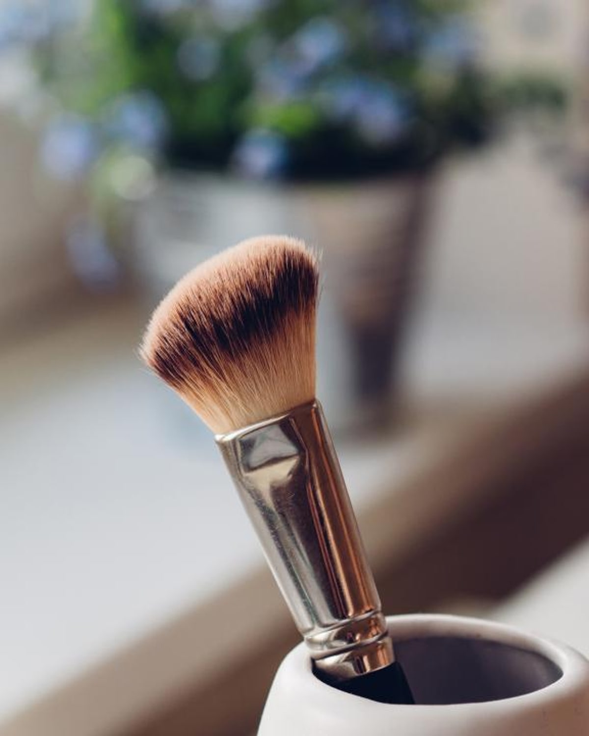 Woman drying her fine hair with a round brush at home